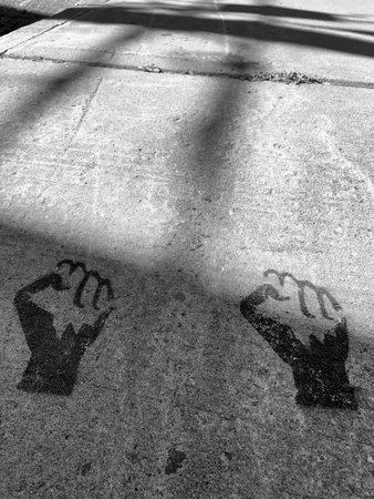 Black and white image of a pair of closed human hands printed on the sidewalk.の写真素材