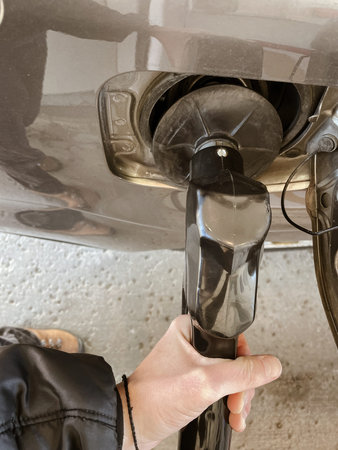 Hand refilling a car with gasoline at a gas station, closeup