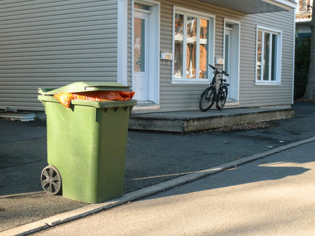 Green garbage bin in front of a house in the city.の写真素材