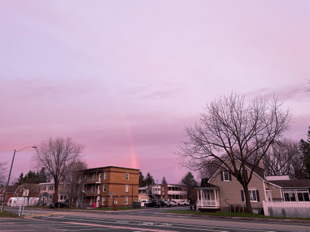 Colorful sunset over a small town in Quebec city with a rainbow in the skyのeditorial素材