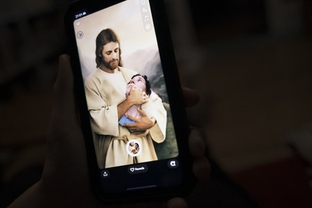 Woman using a cell phone to take a photo of herself in the arms of Jesus.のeditorial素材