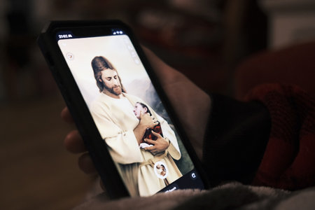 Woman using a cell phone to take a photo of herself in the arms of Jesus.のeditorial素材