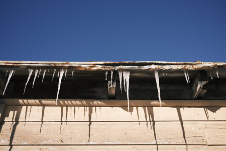 Icicles hanging from the roof of a house in winterの写真素材