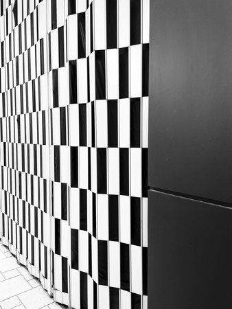 Abstract black and white background of a wall with black and white tiles. A closed store gate in a...