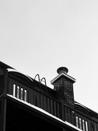 Black and white photo of a chimney on the roof of a houseの写真素材