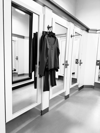 Black and white image of fitting rooms in a store with black clothes on hangersの写真素材