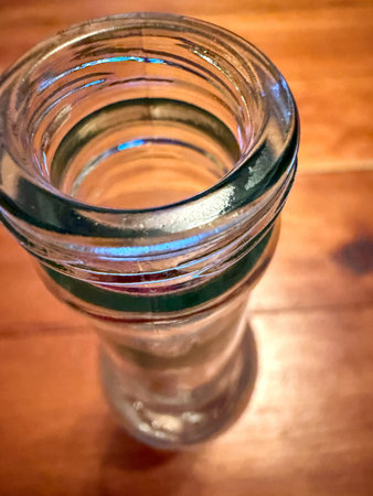 Empty glass bottle on a wooden table, close-up shot.
