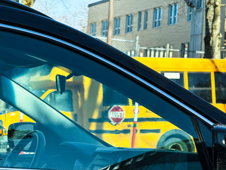 View of a yellow school bus from the side of a car on a sunny day in the city.