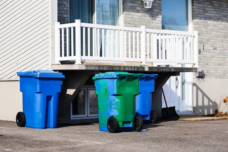 Blue garbage bins in front of a house.