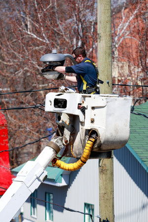 A worker changes the light on a city street lamp.