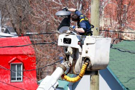 A worker changes the light on a city street lamp.