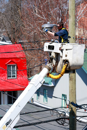 A worker changes the light on a city street lamp.