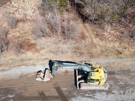 Excavator working on a road construction site in early spring. Volvo machinery on a new construction...