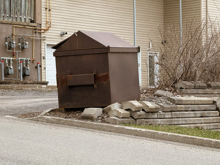 Old metal trash bin on the street in front of a house