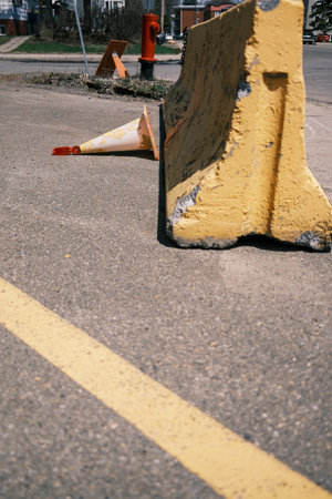Traffic cone on the street with broken yellow wall in city.の写真素材