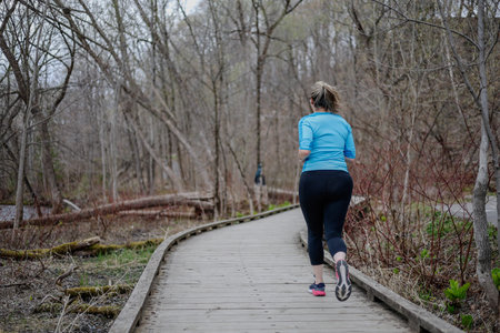 Athletic woman running on a boardwalk in the woods