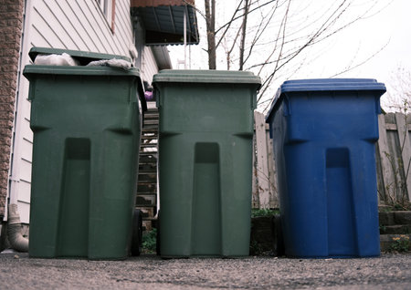 Trash cans in front of a wooden fence in the yard.の写真素材