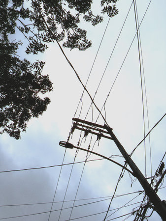 Old wooden pole with wires and cables in the sky, vintage style. Electricity post with blue sky.