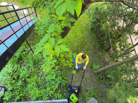 A man mowing the lawn in the yard. View from above. Aerial view of a man mowing the lawn.