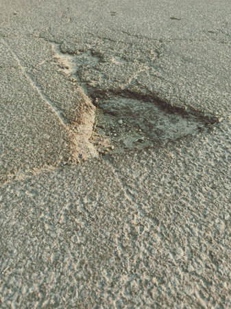 Close up of broken asphalt road with potholes and cracks.の写真素材