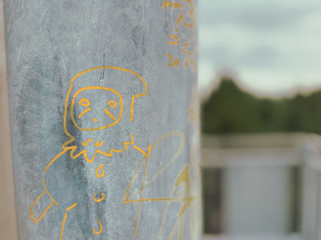 Drawings and graffiti on a metal pole in the city.