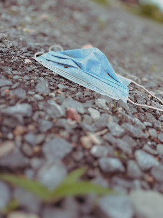 Surgical mask thrown on the ground. Environmental pollution. Selective focus.