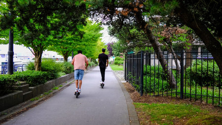 People riding electric scooters in the park, rear view