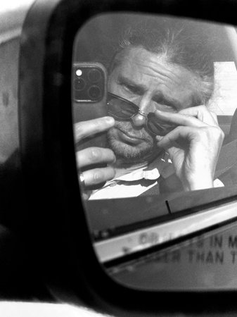 Man in sunglasses taking a selfie in a car. Black and white photos. Self-portrait using a cell...
