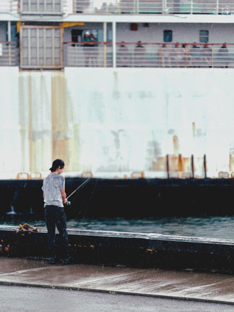 Boy fishing in the rain on the dock.