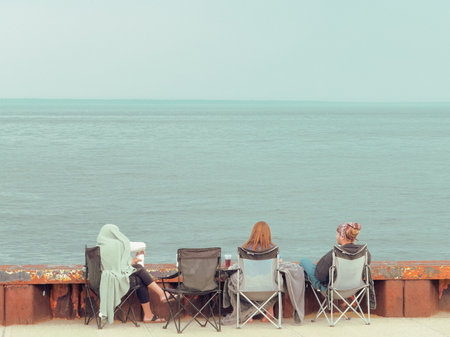 Group of people sitting on the quay and looking at the sea