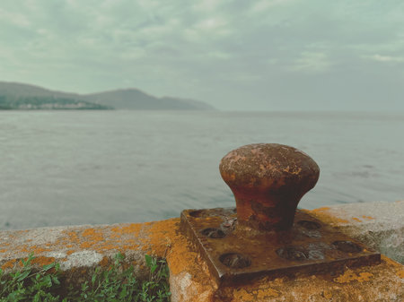 Old rusty bollard on the seashore. Selective focus