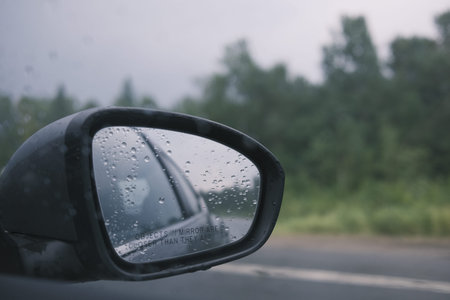 Raindrops on the rear view mirror of a car in the rainの写真素材