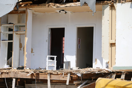 Demolition of an old house with a yellow excavator at a construction site. Demolition of an apartment block with an excavator.のeditorial素材