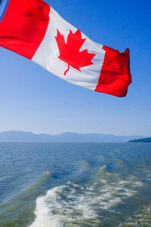 Flag of Canada waving in the wind on the background of the lake