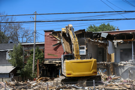 Demolition of an old house with a yellow excavator at a construction site. Demolition of an...