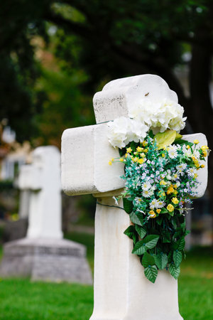 Cross with flowers on the background of the grave in the cemetery in Quebec