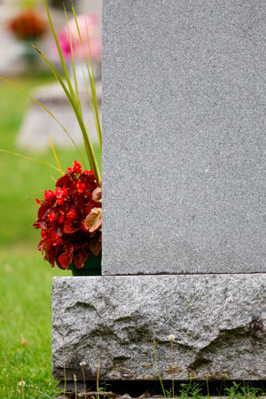 A close up shot of a gravestone at a cemetery with flowers.の写真素材