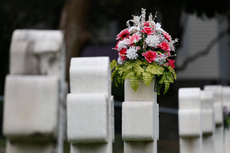 A close up shot of a gravestone at a cemetery with flowers. Cross with flowers on the background of the grave in the cemetery in Quebec.の写真素材
