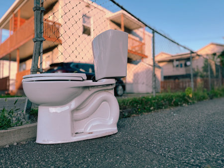 White toilet bowl on the street in front of a private house.