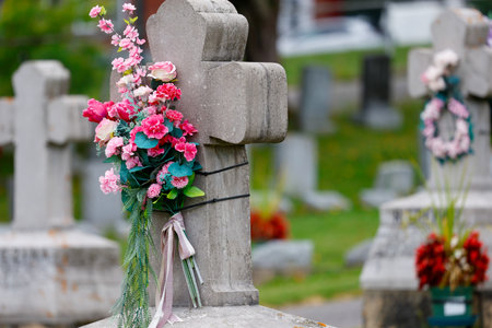 Cemetery with a stone cross and a bouquet of flowers.の写真素材