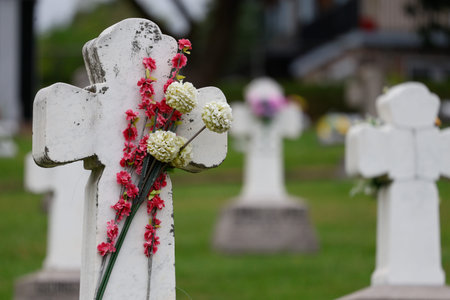 Cemetery with a stone cross and a bouquet of flowers.
