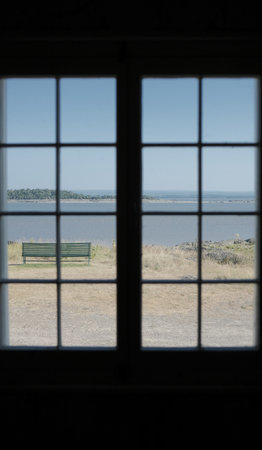 A view through the window of a room with a bench and a lake in the backgroundの写真素材