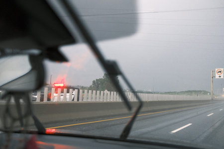 View from the car on the road with a police car driving at high speed on the highway during a rainy...