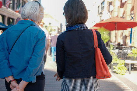 Rear view of two women walking together in the street with their backs to the camera