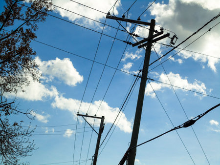 High voltage power lines against the blue sky with clouds. Electricity distribution.