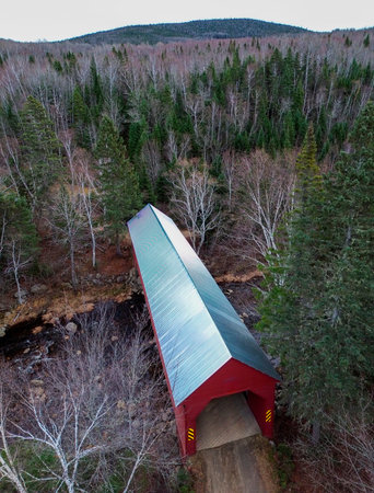 Aerial view of a bridge over a river in the forest. An old covered bridge in the forest of Quebec,...