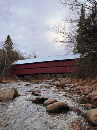 A wooden covered bridge over a stream in the middle of a forest, Quebec, Canada.