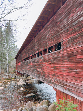 A wooden covered bridge over a stream in the middle of a forest, Quebec, Canada.