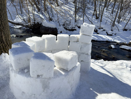 building an igloo on the riverbank in the forest in winter
