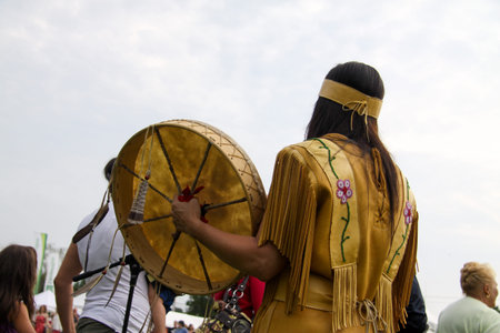 Native American woman in traditional dress with a traditional drum during the annual powwow, Quebec,...